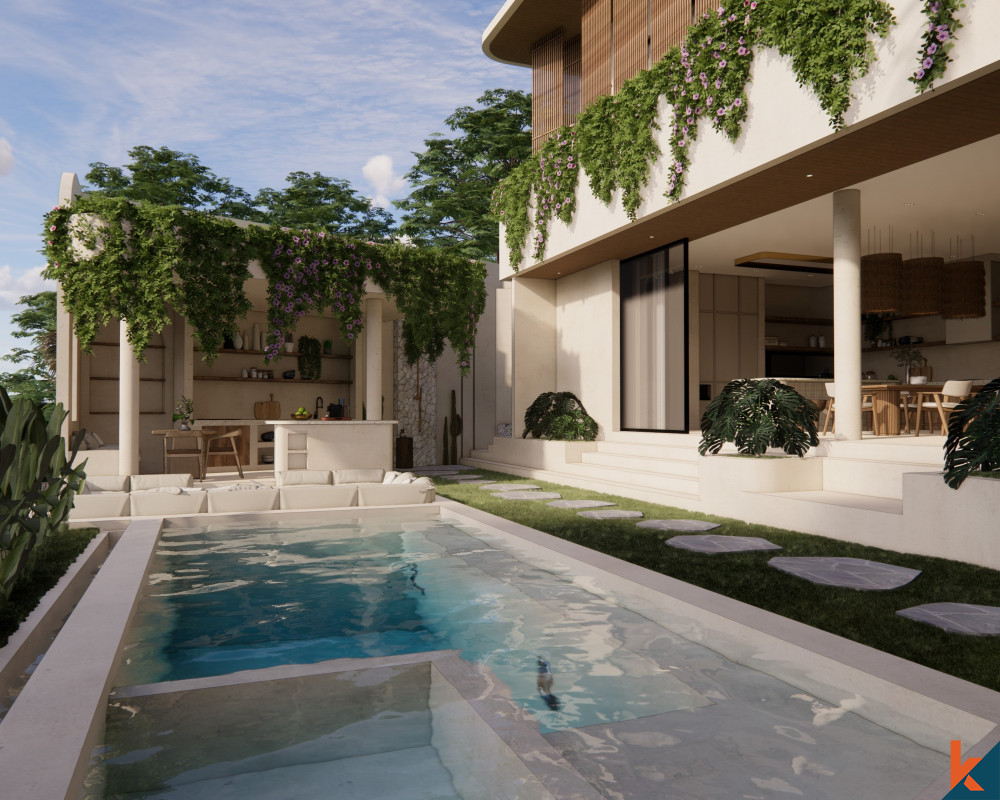 An elegant outdoor living space in a modern villa, characterized by a rectangular swimming pool, stepping stones, and a lounge area. The villa's façade is adorned with cascading greenery and flowers, while the open-concept kitchen and dining area in the background extend the living space into the outdoors.