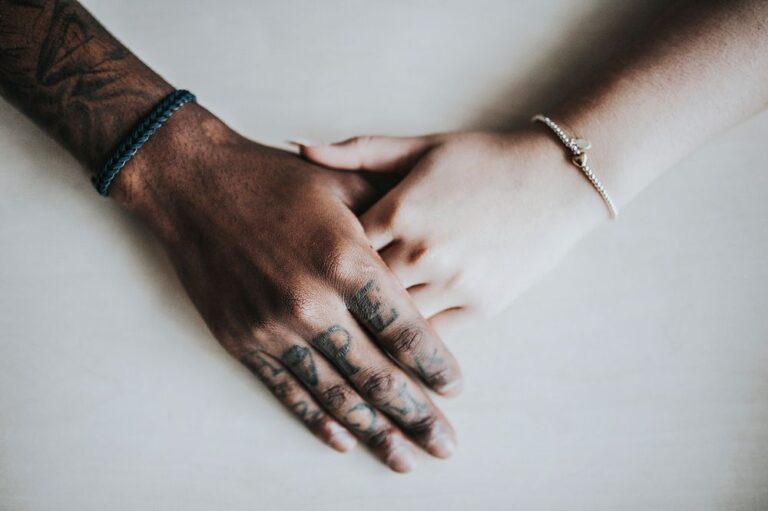 two hands, one with many tattoos